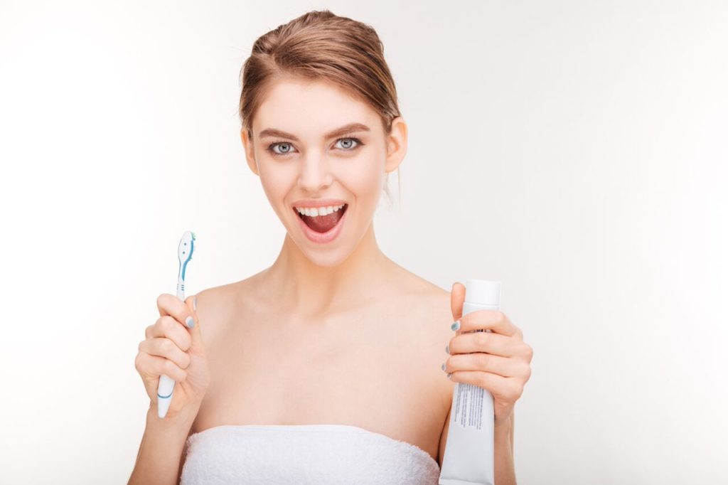 A woman holding a toothbrush and a toothpaste tube - Mississauga Dentist - Bristol Dental